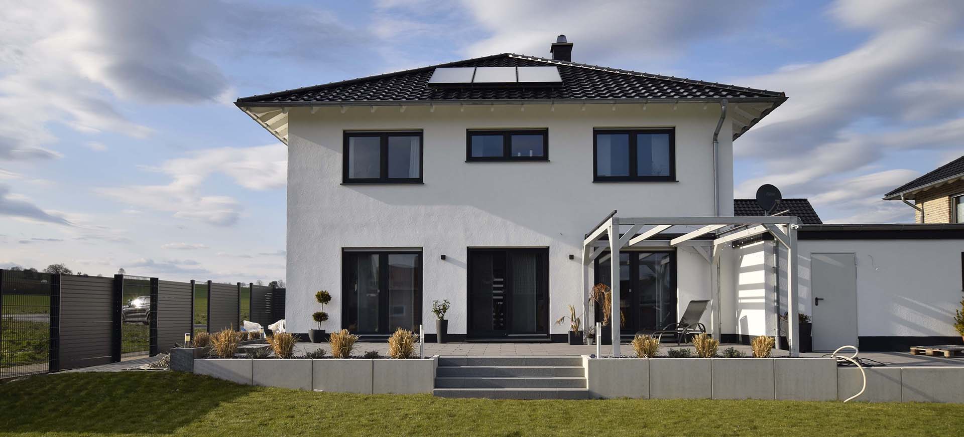 Ein weißes Massivhaus mit Garten und Terrasse